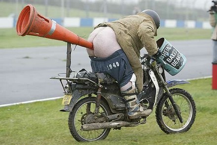 Man on motorbike with beans by the handlebars and a large nozzle up his butt.