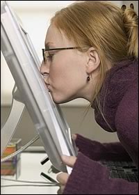 Cute nerd-girl smooches a computer monitor