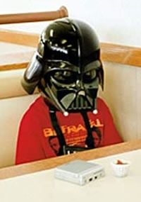 A sad-looking kid in a Darth Vader sitting at a fast food restaurant table