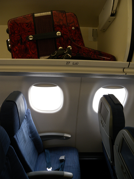 Joey deVilla's red Silvetta accordion in the overhead bin above his airplane seat