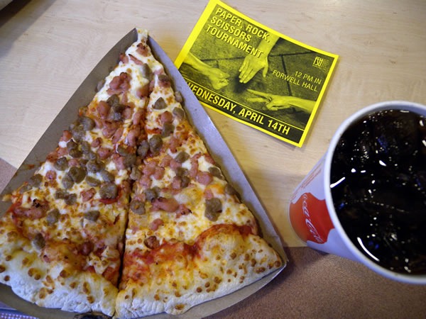 Slice of pizza, glass of coke and a flyer for a "Rock/Paper/Scissors tournament"