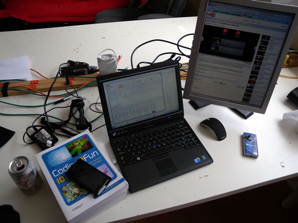 HacklabTO work table with my laptop plugged into a monitor, mouse, "Coding4Fun" book and can of Diet Coke