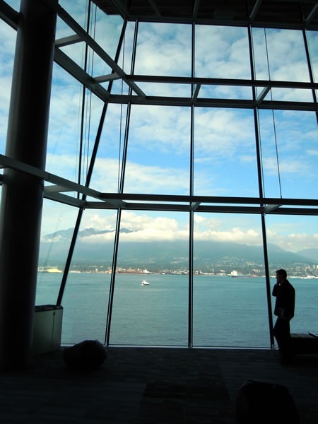 A silhouetted TechDays attendee takes a phone call against the north windows of the Vancouver Convention Centre's West Building, with the oceans and mountains in the background