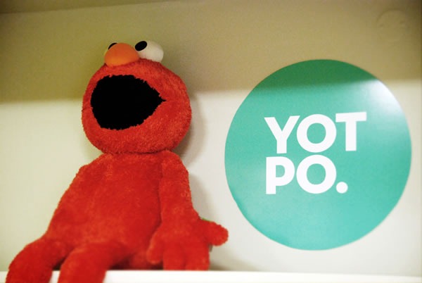 An Elmo doll sitting beside the Yotpo logo