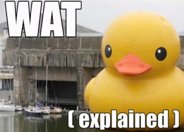 Giant rubber duck floating in a harbour and dwarfing the sailboats beside it