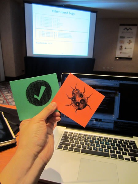 Joey deVilla holding up "Feature" and "Bug" cards in front of his laptop.