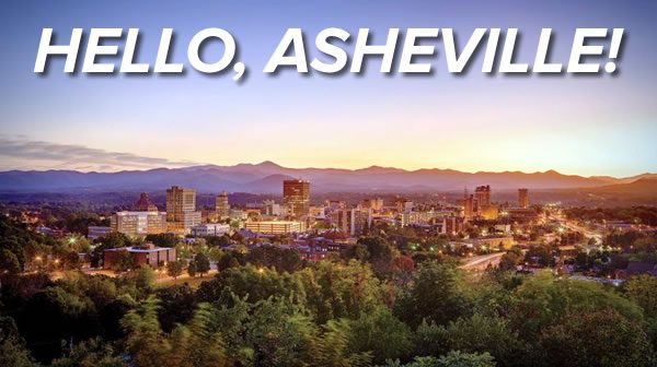 Photo: The city of Asheville, North Carolina in the sunset (or sunrise), with forest in the foreground and mountains in the background. Heading: HELLO, ASHEVILLE!