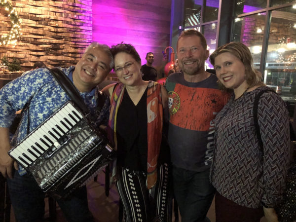 Photo: From left to right, Joey deVilla (with accordion), Lyssa Adkins, Alistair Cockburn, and Anitra Pavka smile at an Agile Social party at Copper Shaker, St. Petersburg, Florida, December 17, 2018.