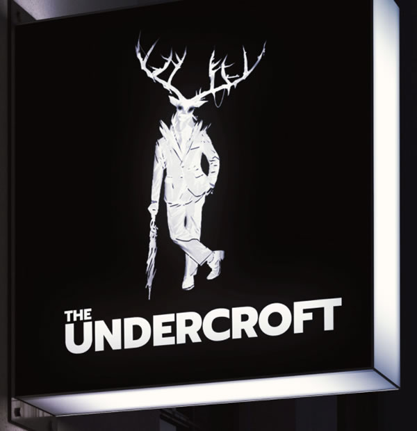 Photo: The Undercroft sign, featuring the Undercroft’s “mascot” — a stag standing upright in a suit, leaning jauntily against an umbrella, walking stick-style.