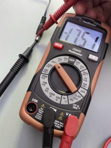 Multimeter being used to measure voltage coming from adapter, with the display showing a negative voltage.