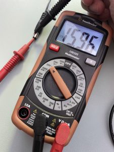 Multimeter being used to measure voltage coming from adapter, with the display showing a positive voltage.