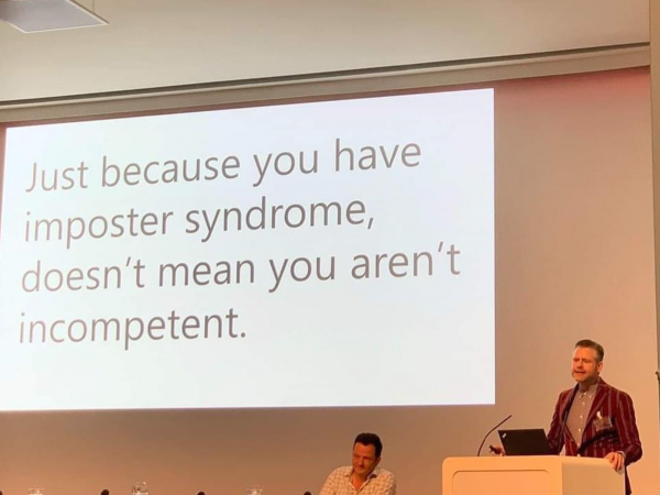 Presenter showing slide that reads: “Just because you have impostor syndrome doesn’t mean you aren’t incompetent.”